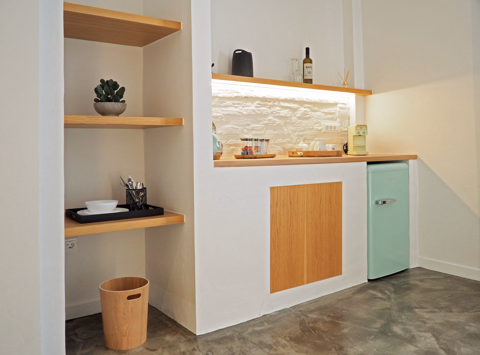 Minimalist kitchen corner with wooden shelves, countertop, light blue mini fridge, and small appliances.
